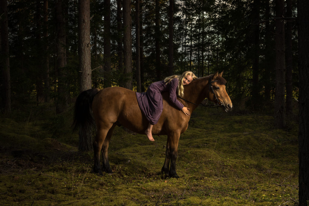 Flicka med sin häst i skogen